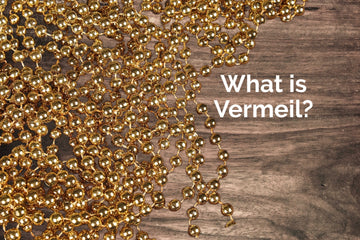 gold bead chain on a background of dark wood. A blog post explaining what is vermeil.