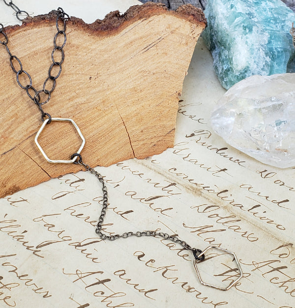 Y necklace draped over piece of tree and surrounded by crystals