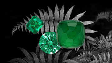 Emerald is the birthstone for May. Image of three facets emeralds with black and white image of a fern in the background.