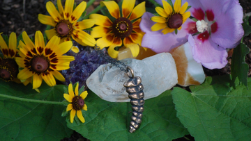 Bronze rattlesnake rattle necklace surrounded by flowers and quartz