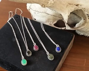 kbeau jewelry five pendants with different stones lying on black block of wood with deer skull