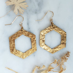 hammered brass hexagonal earrings on white marble background