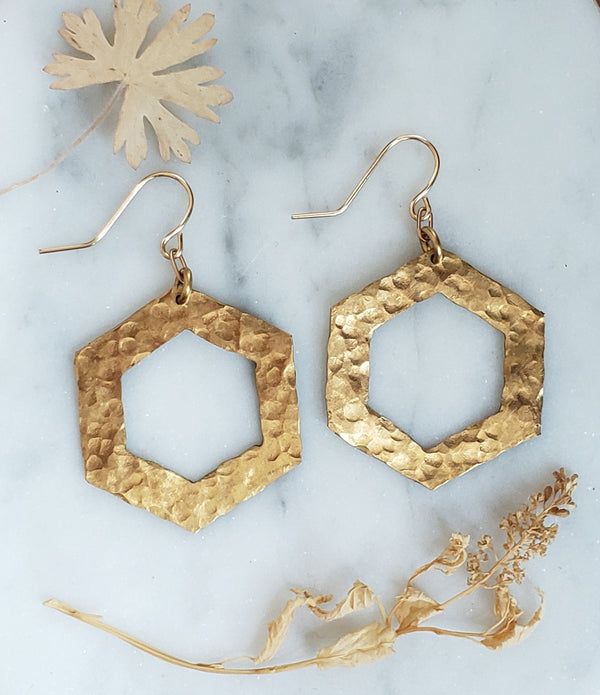hammered brass hexagonal earrings on white marble background