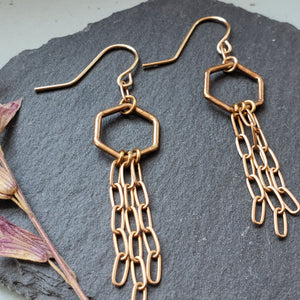 small bronze hexagons with bronze chains fringe on gold fill ear wires slate background with dried flower