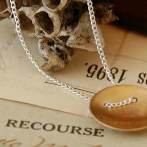 A bronze domed disc on a sterling silver chain