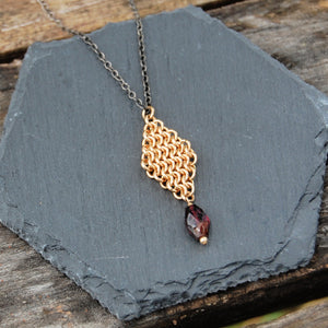gold pendant with garnet drop on sterling silver chain that is darkened