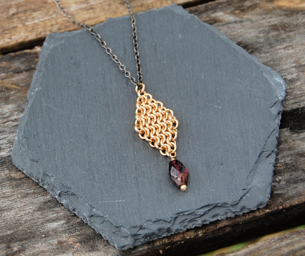gold pendant with garnet drop on sterling silver chain that is darkened